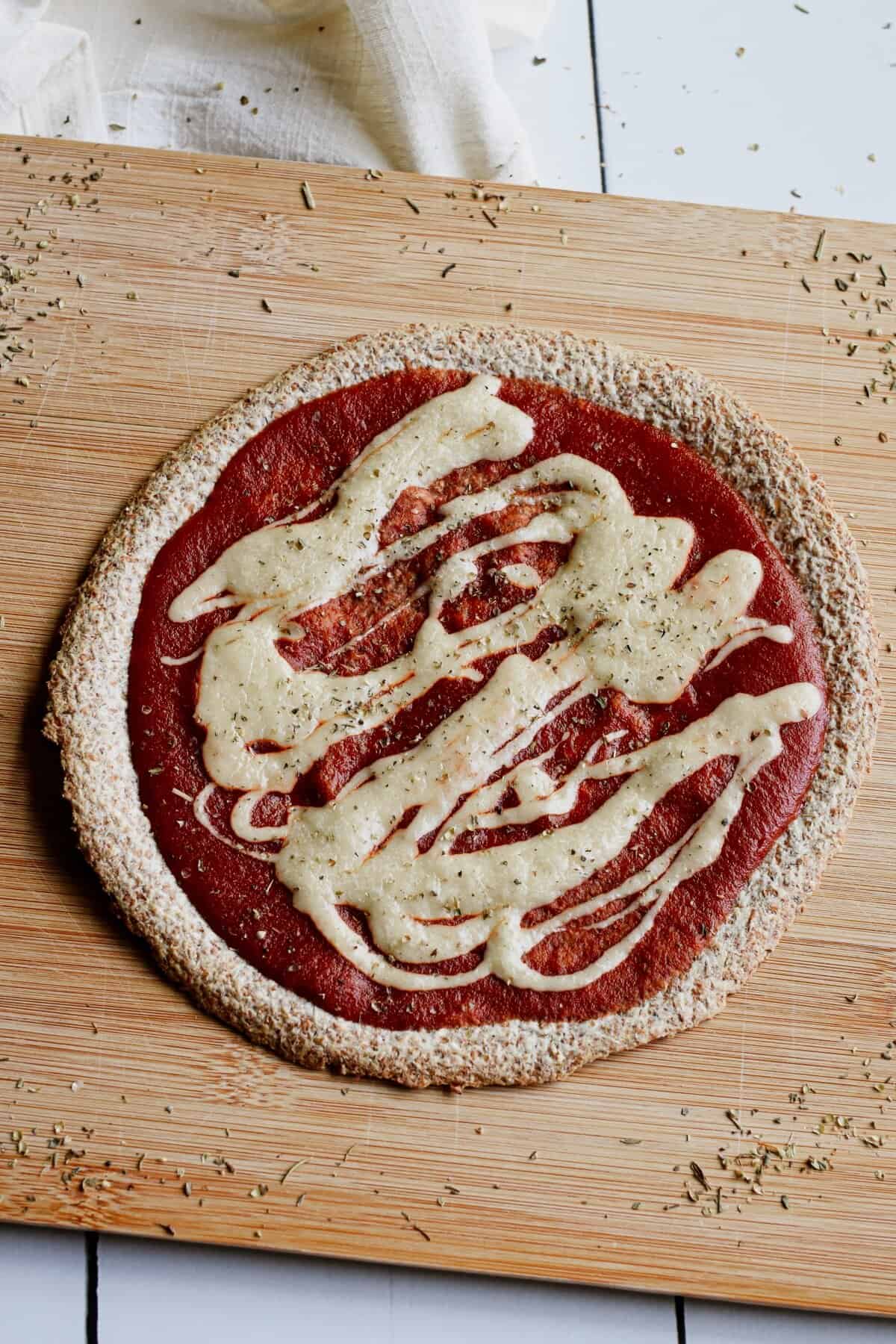 A tortilla pizza with tomato sauce and vegan mozzarella on a wooden board.