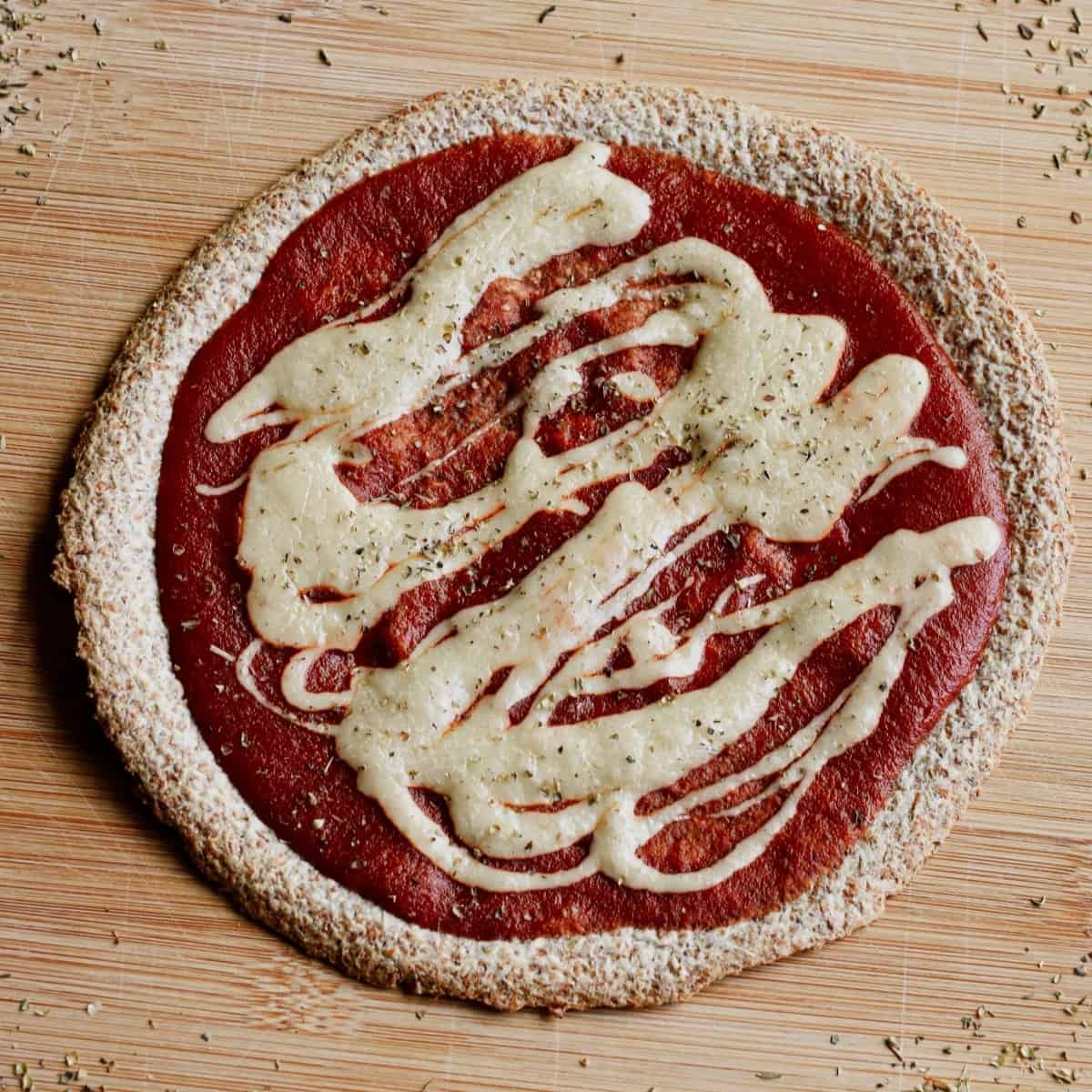 Tortilla pizza with cashew mozzarella on a wooden board.